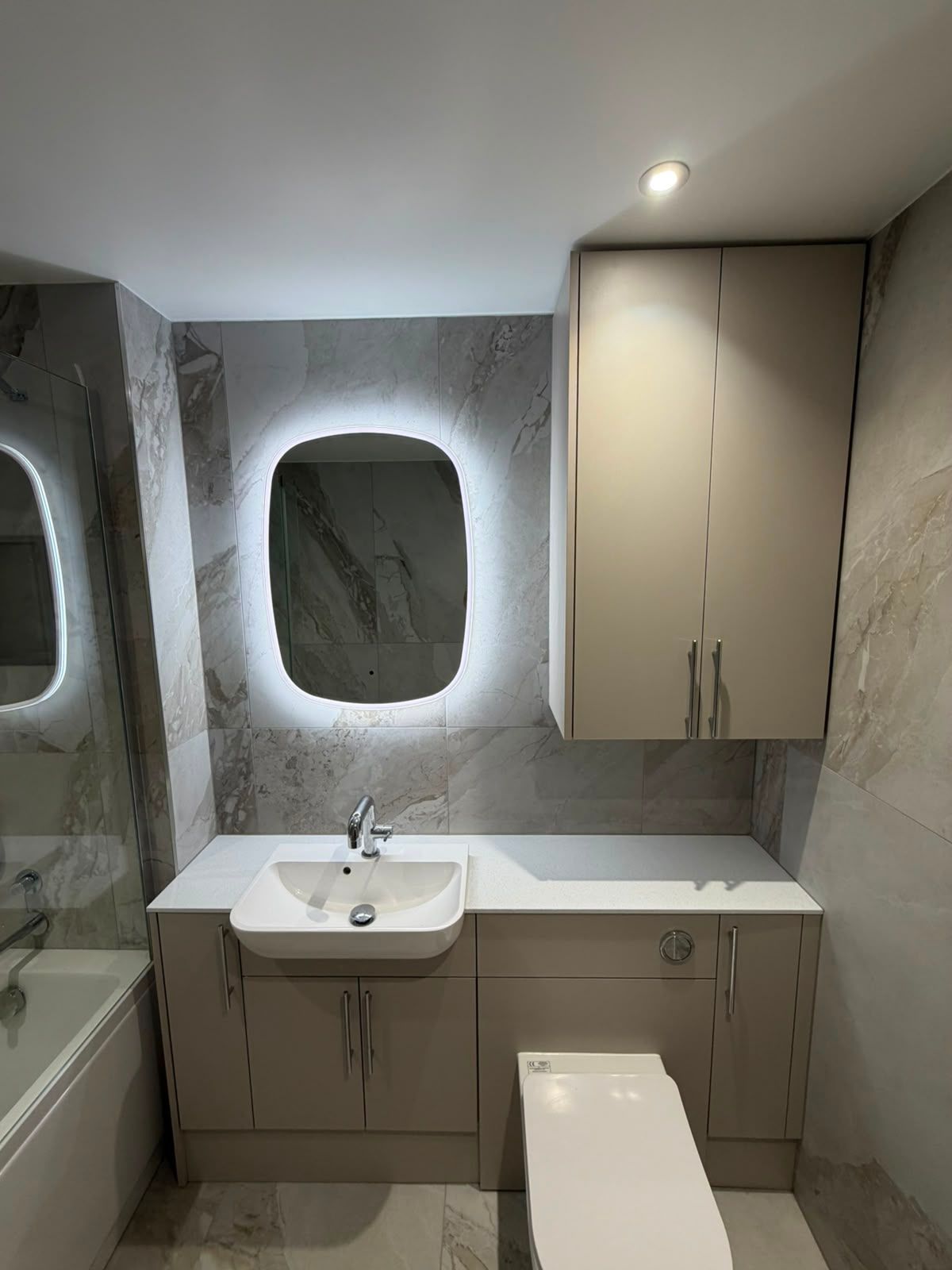 Bathroom renovation lighting with illuminated LED mirror, fitted vanity storage and large format stone effect tiles