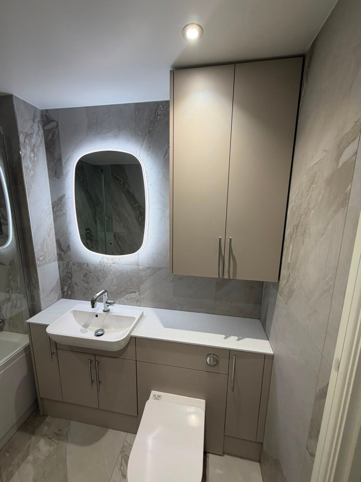 Fitted bathroom vanity units with integrated storage, backlit mirror and stone effect tiles by My Life Interiors