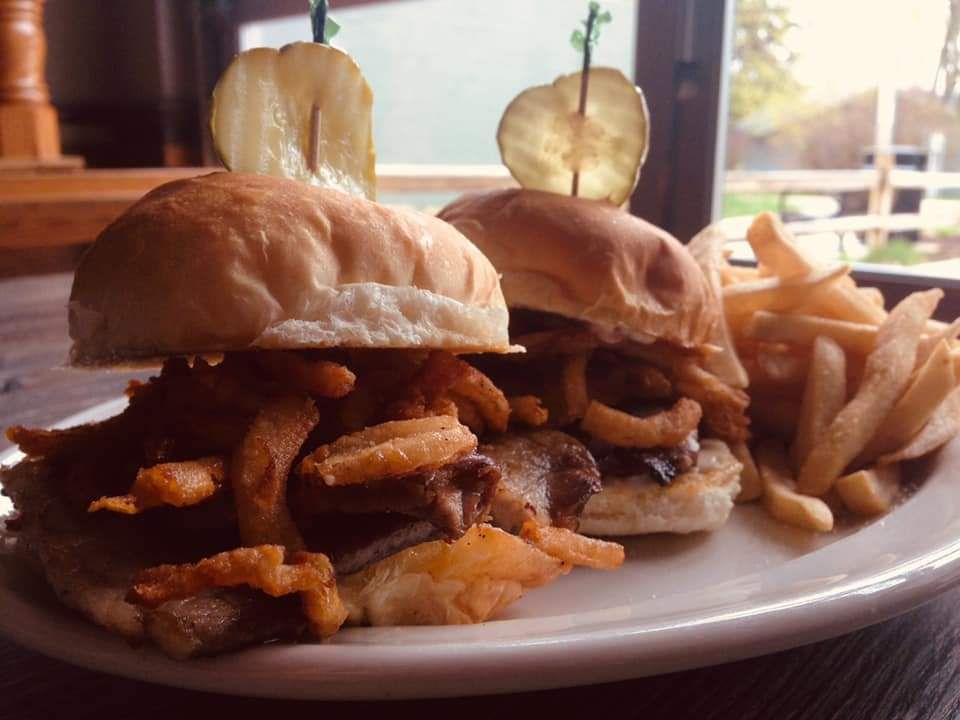 A hamburger and french fries are on a wooden cutting board.