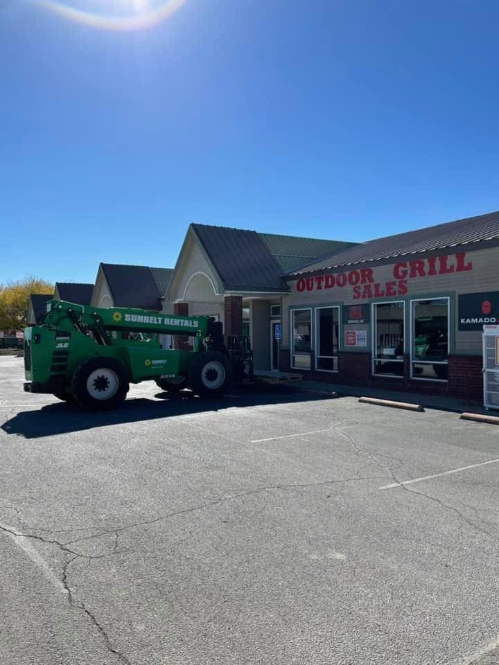 Tractor parked outside a bright-red outdoor grill shop on a sunny day