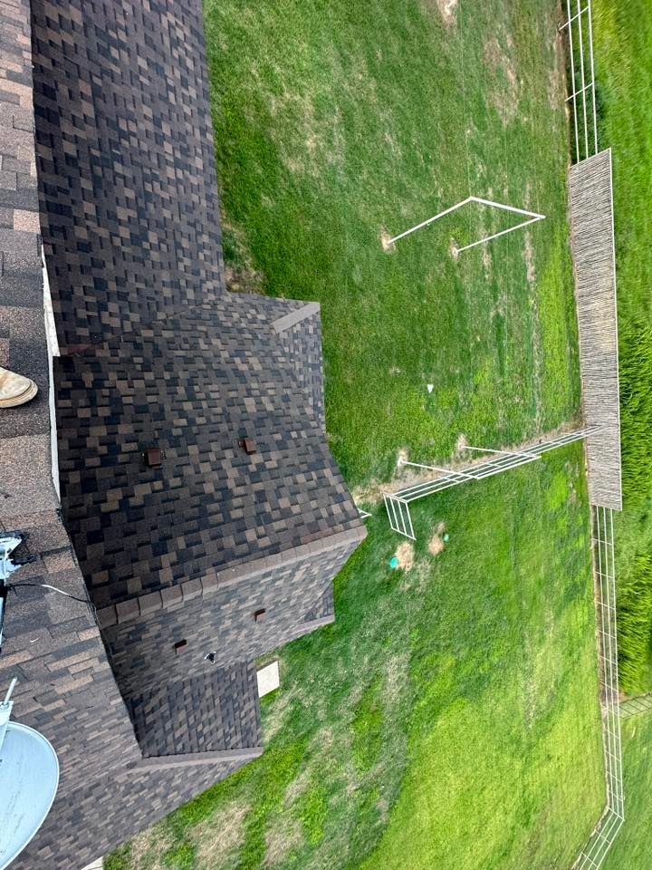 Backyard with green lawn, dark shingled roof, and a white soccer goal near a fence.