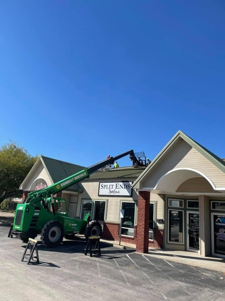 Green crane lifting a sign in front of a storefront under a bright blue sky