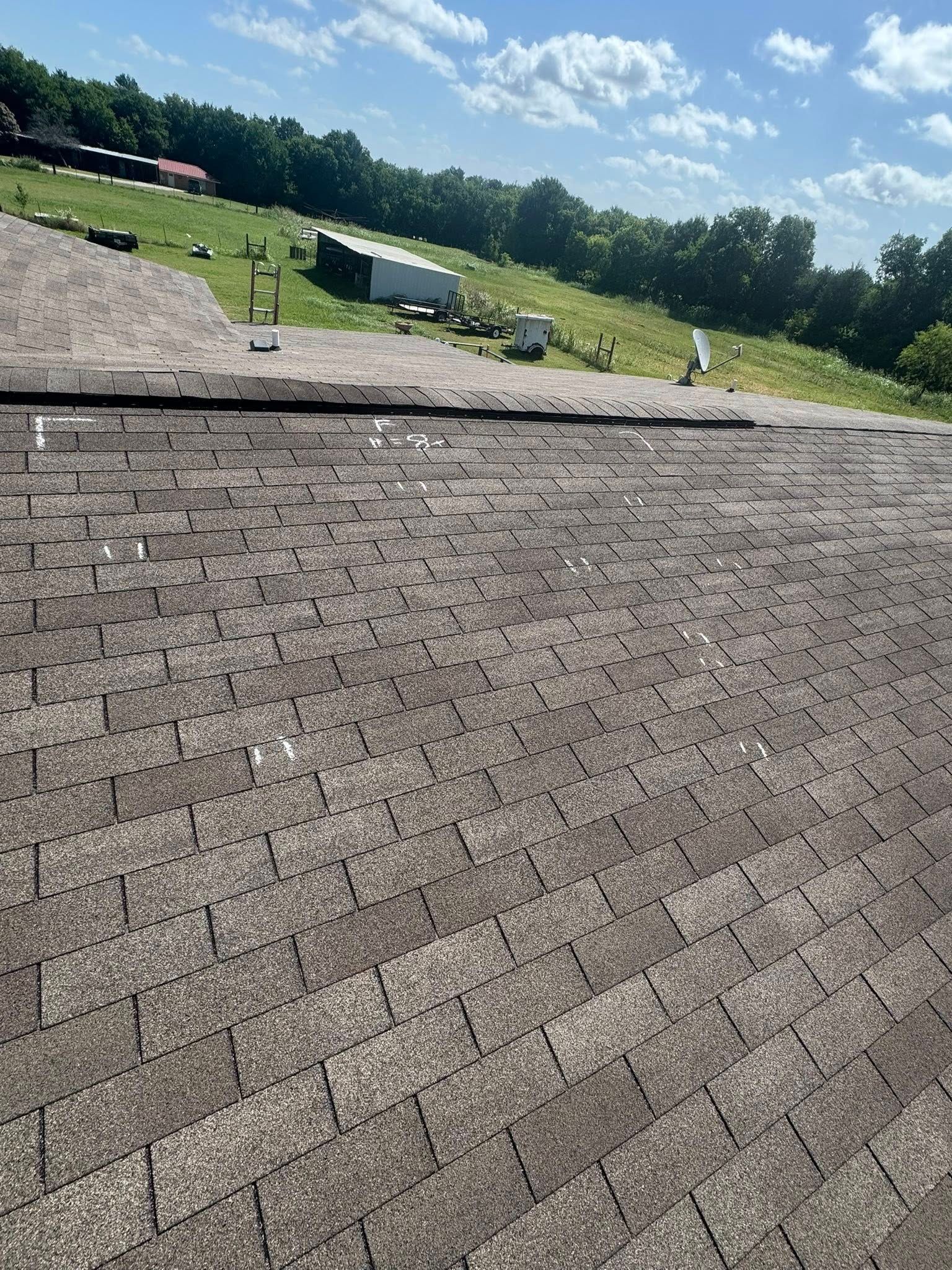 Gravel roof with a grassy hillside, trees, and blue sky in the background