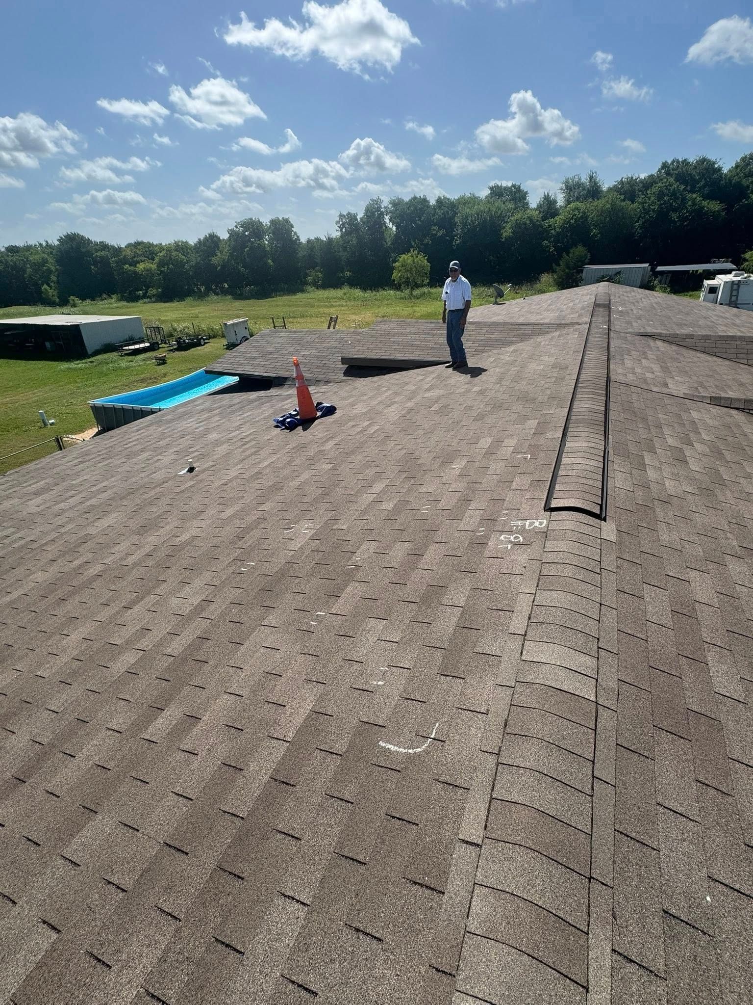 Rooftop under construction with gravel, workers, cones, and blue sky on a sunny day