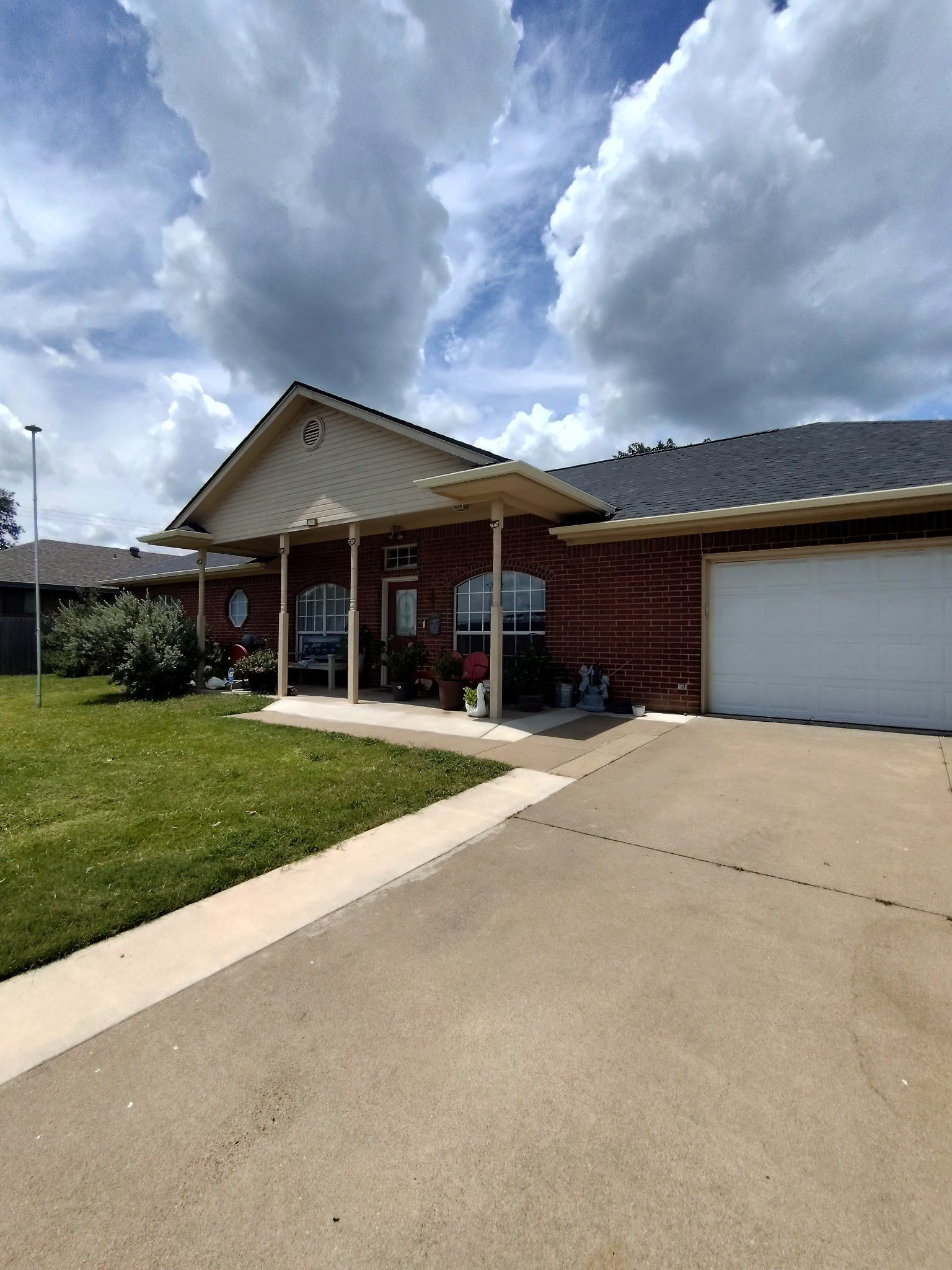 Suburban house with driveway, garage, and front porch under a cloudy sky