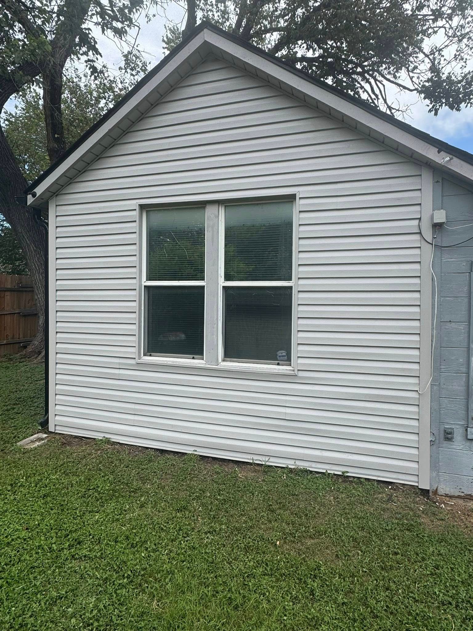 Small white-sided shed with a window and grass lawn in front