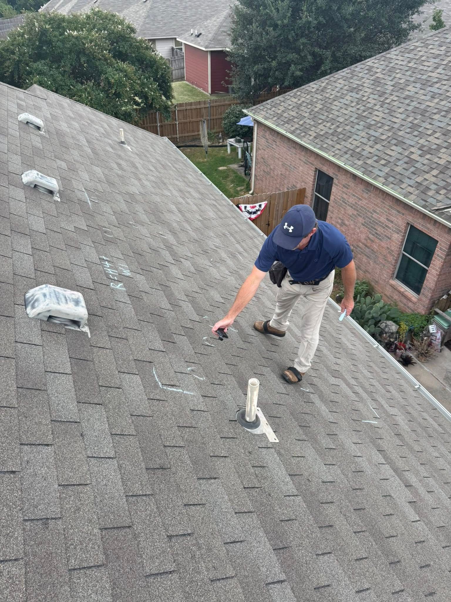 Worker on a steep gray shingle roof installing or inspecting roofing materials.