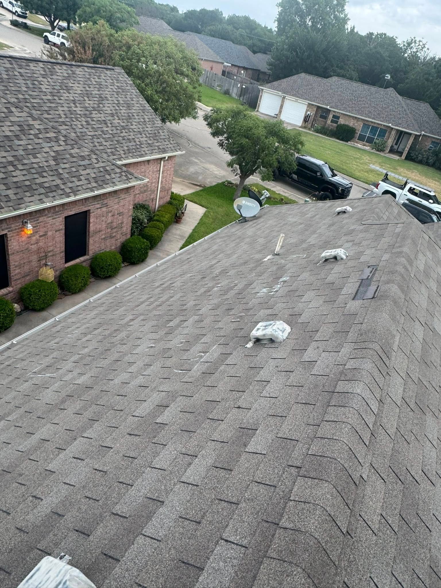 Rainy suburban rooftops with scattered white debris and a parked black car below