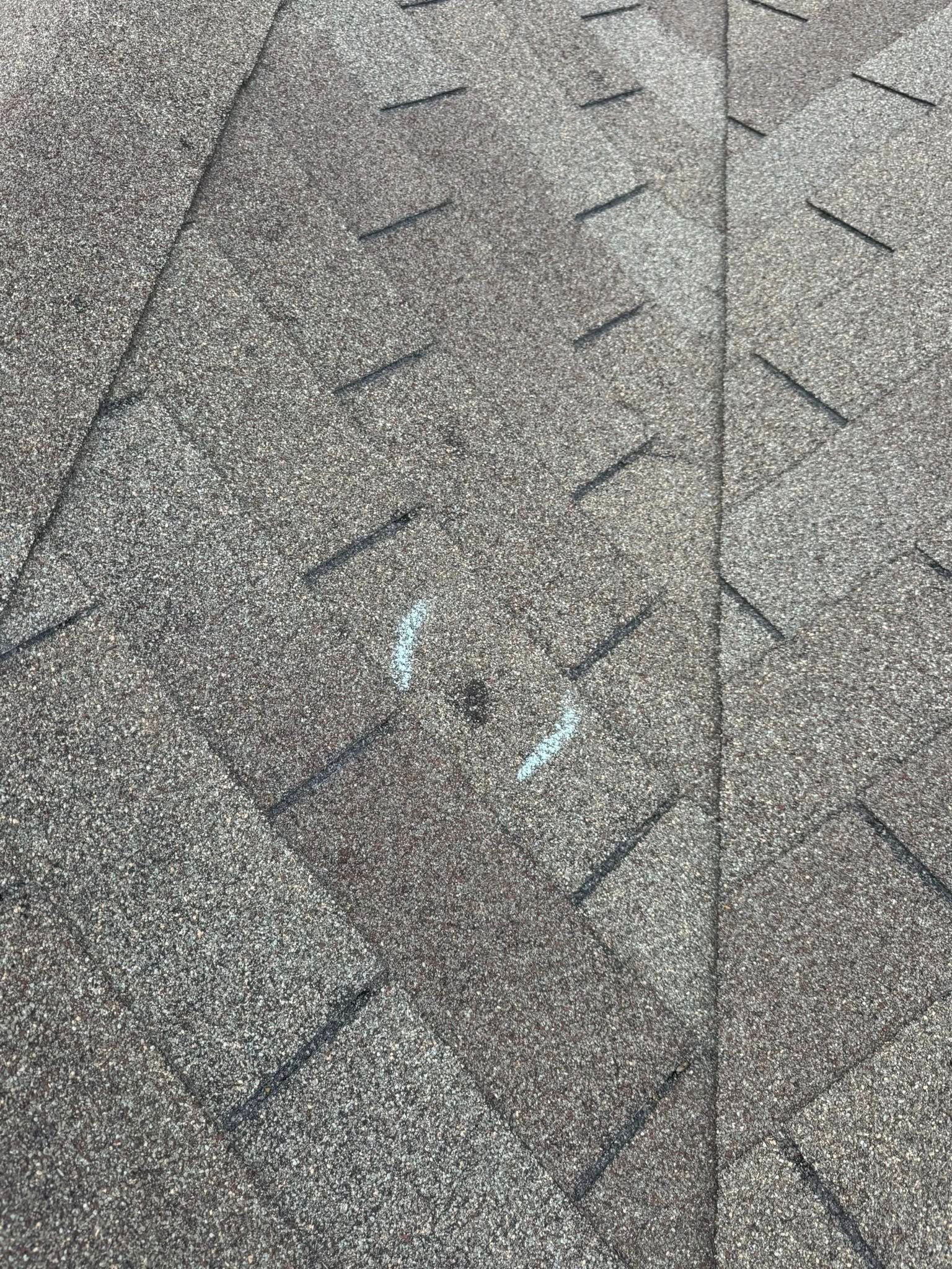Gray shingled roof with a dark diagonal seam and faint blue chalk marks near the center