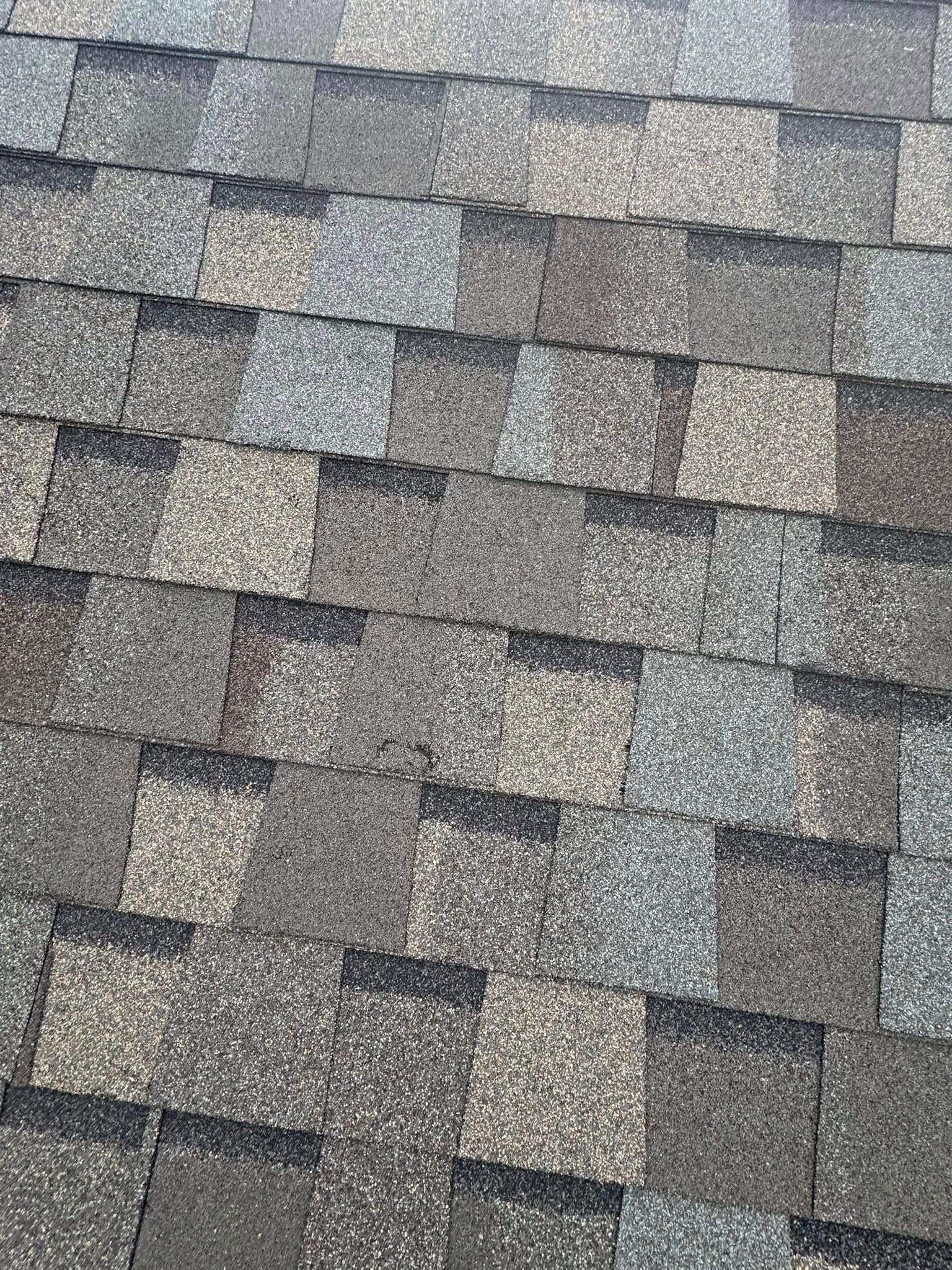 Gray asphalt roof shingles in a close-up pattern with weathered texture
