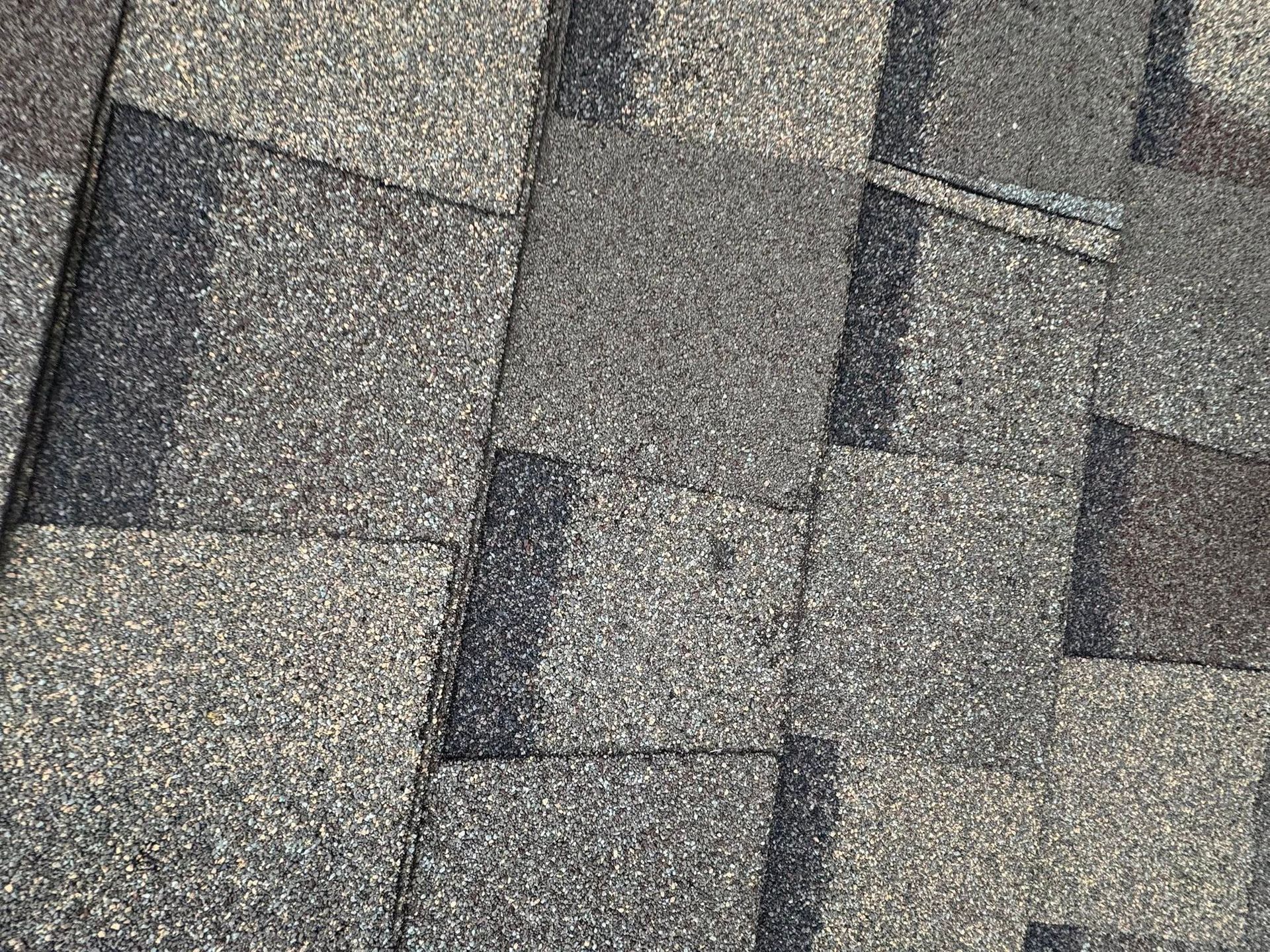 Close-up of gray asphalt roof shingles in a repeating pattern