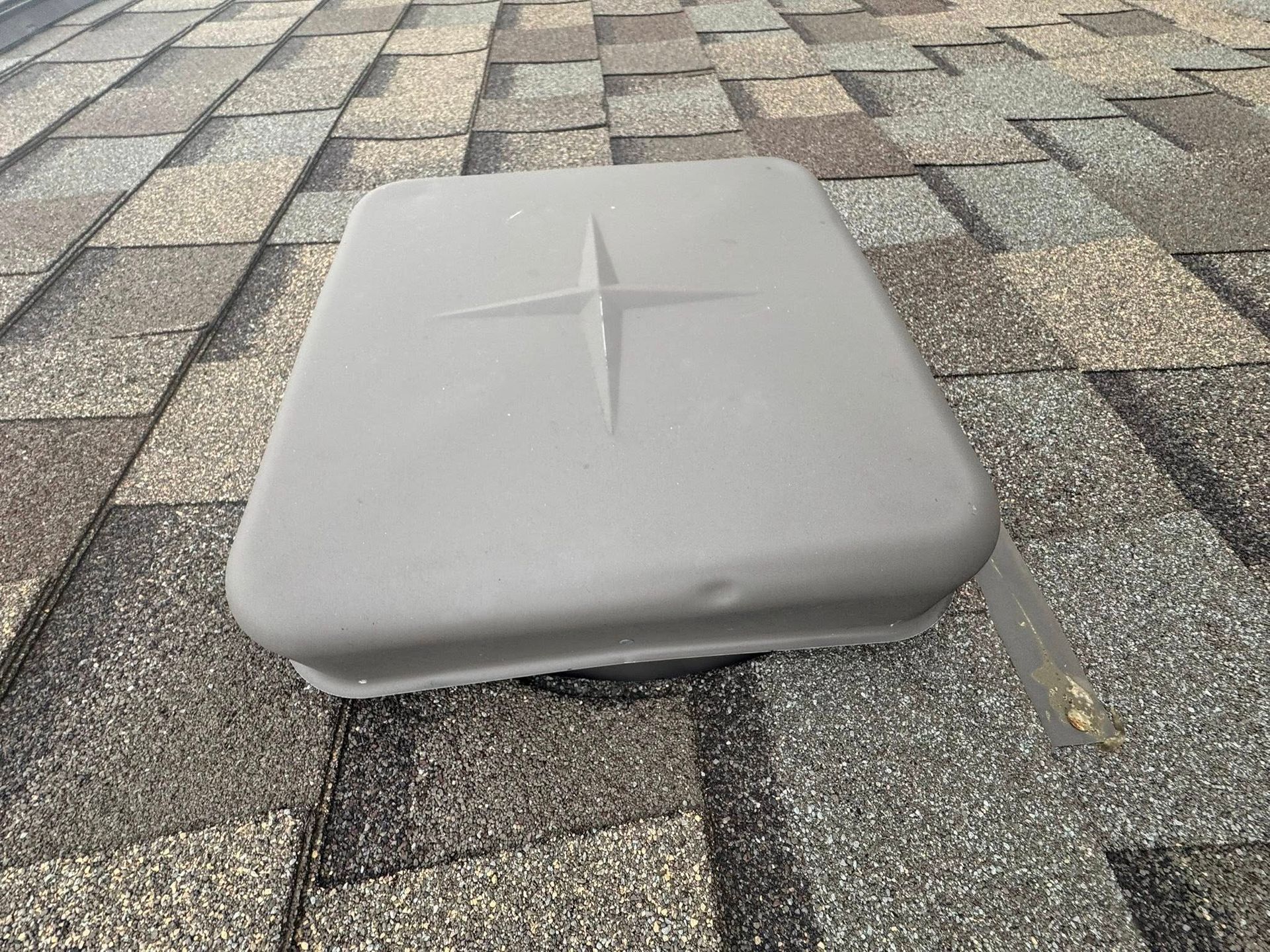 Gray cushioned square seat or stool on a paved stone surface outdoors