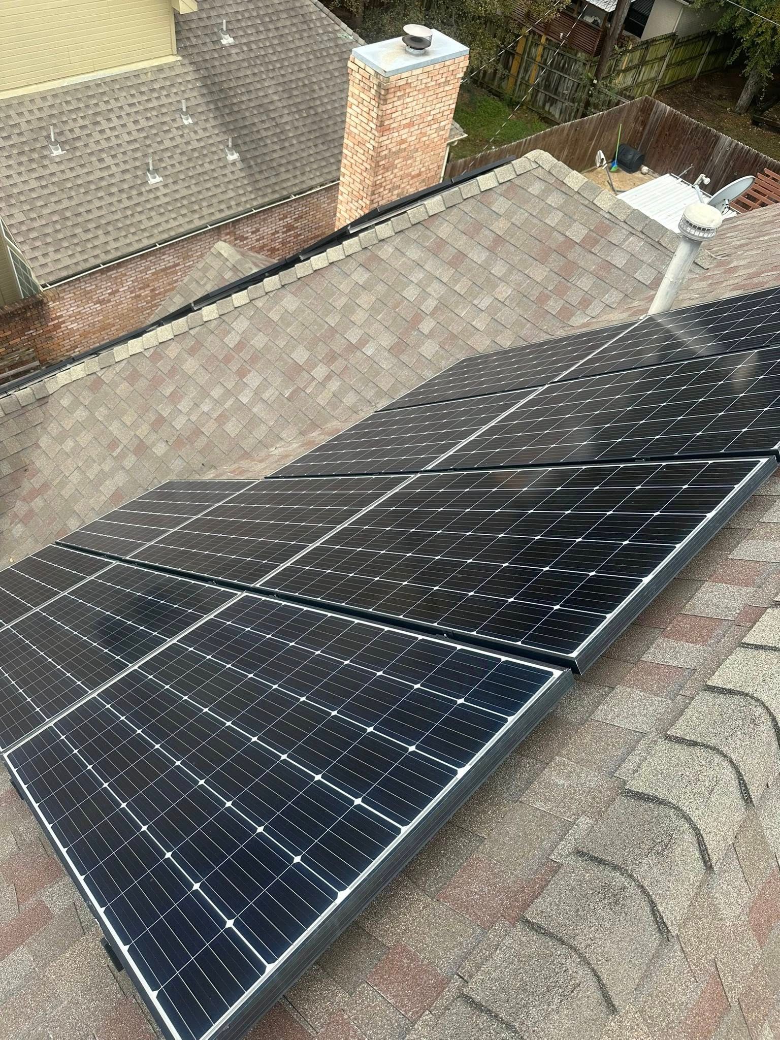 Solar panels installed on a sloped rooftop beside a brick chimney.