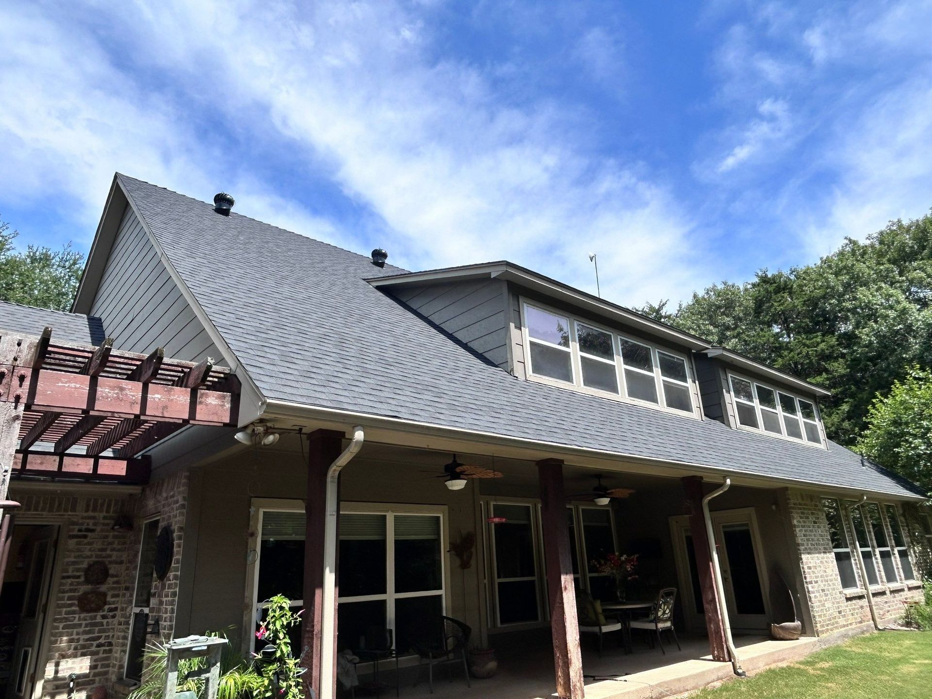 House with steep gray roof and covered porch under a blue sky