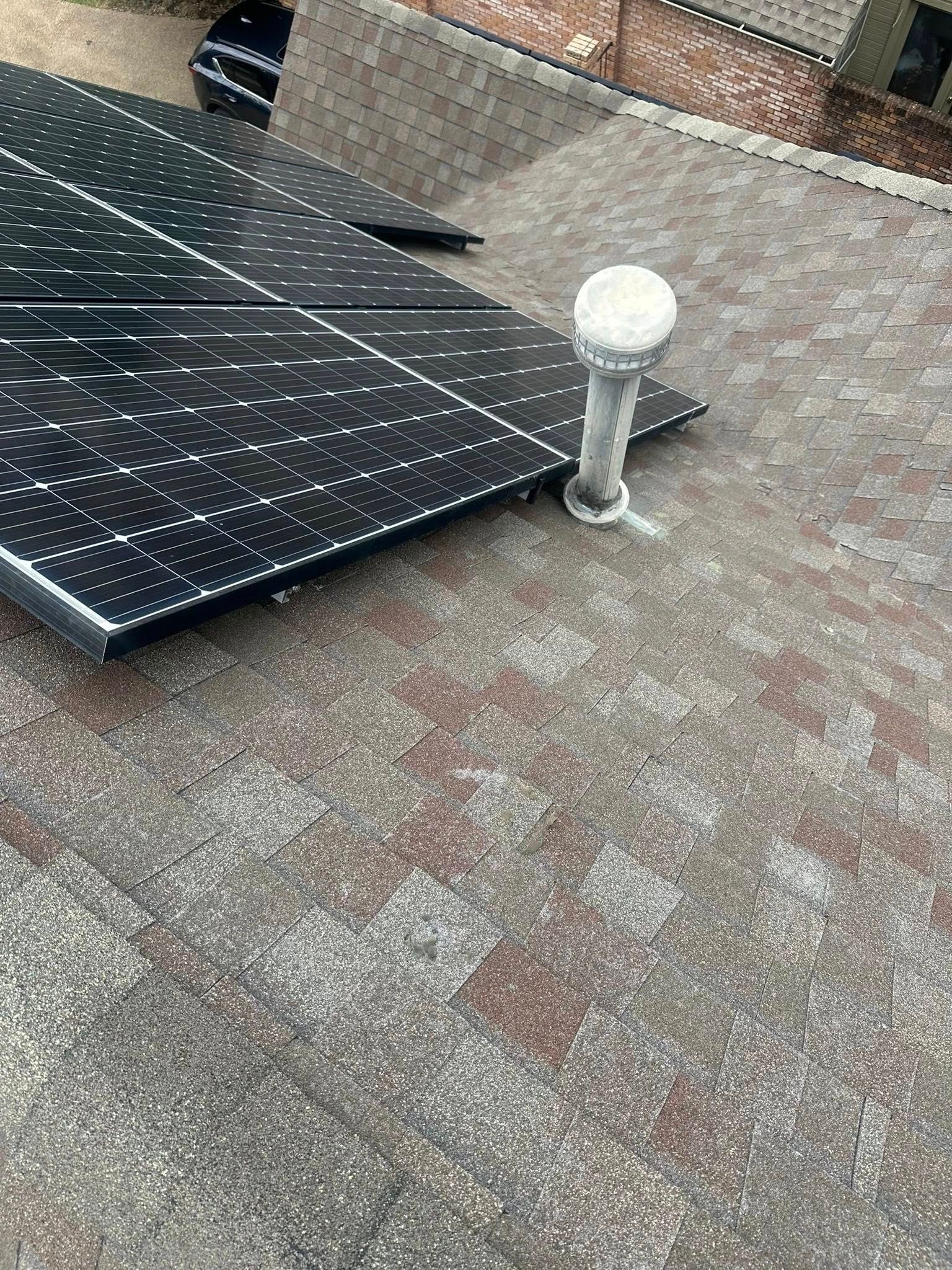 Solar panel mounted on a rooftop beside a small white light fixture.