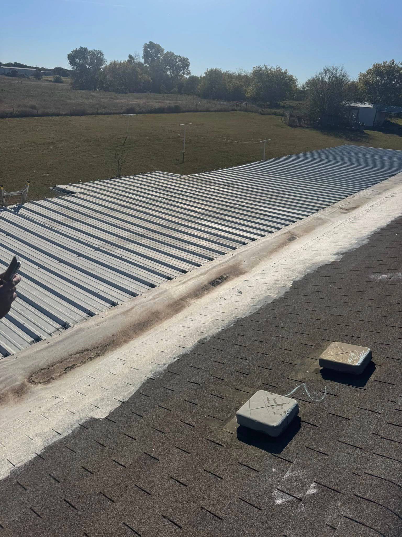 Rooftop with corrugated metal panels, gravel surface, and two concrete blocks under a clear sky.