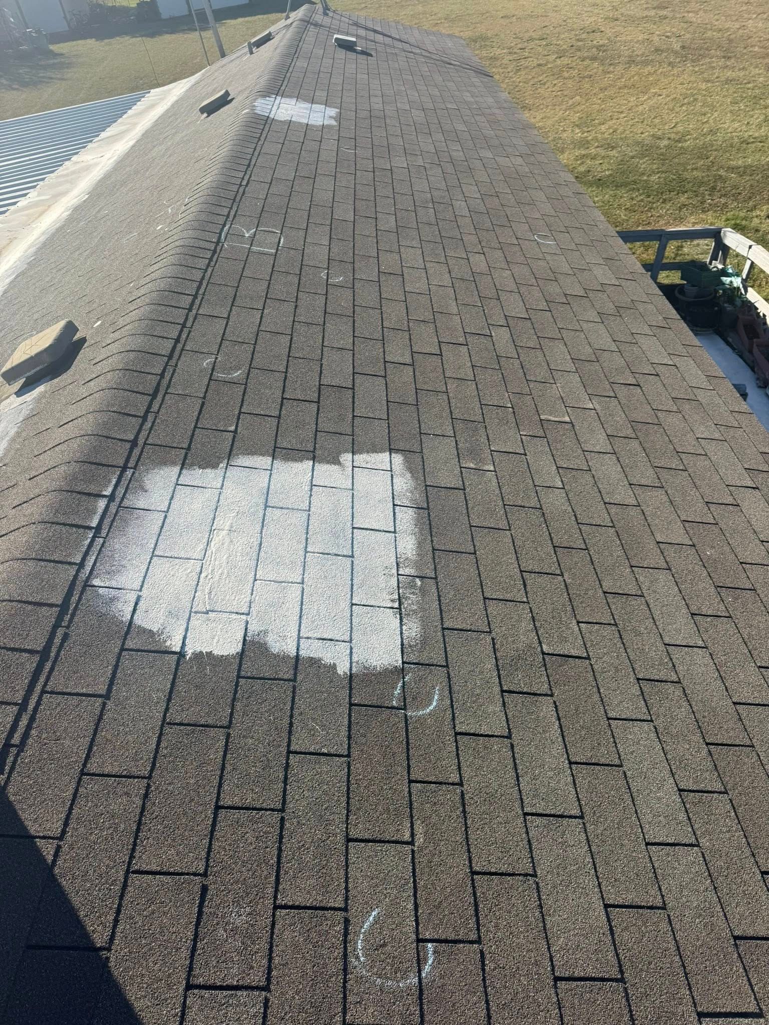 Rooftop with asphalt shingles, a white repair patch, and a skylight near the edge.