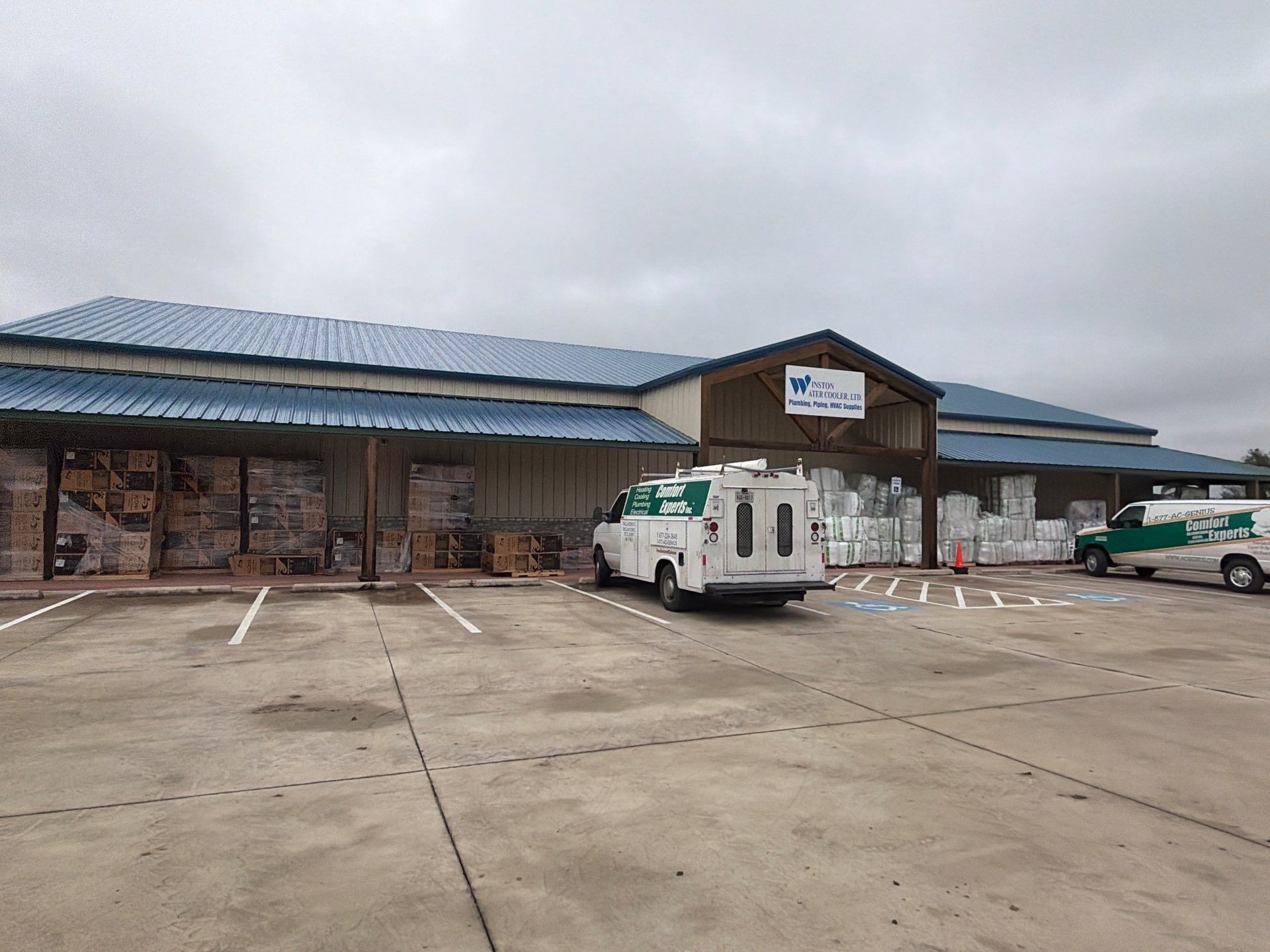 Storefront with blue roof and parked utility vans on a cloudy day