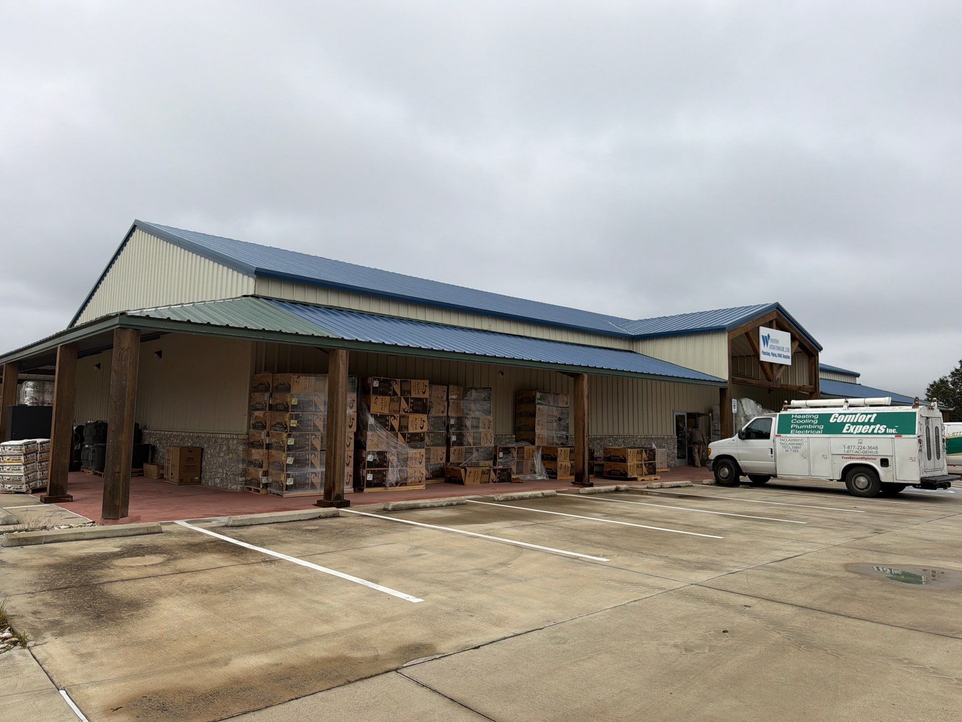Storefront with a blue roof and a white van parked outside on a cloudy day