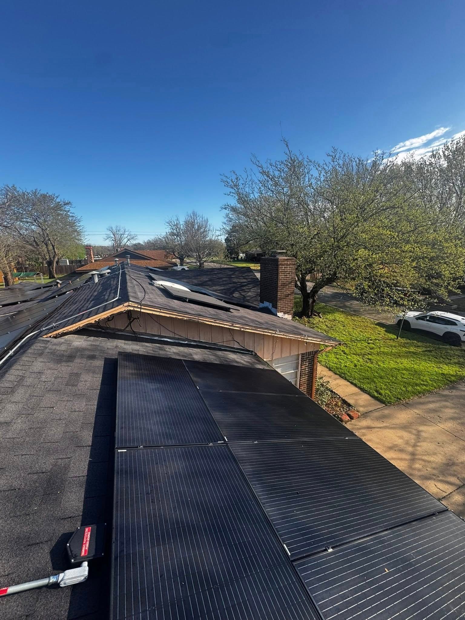 Roof under repair with black underlayment and a partially installed shingle section on a sunny day
