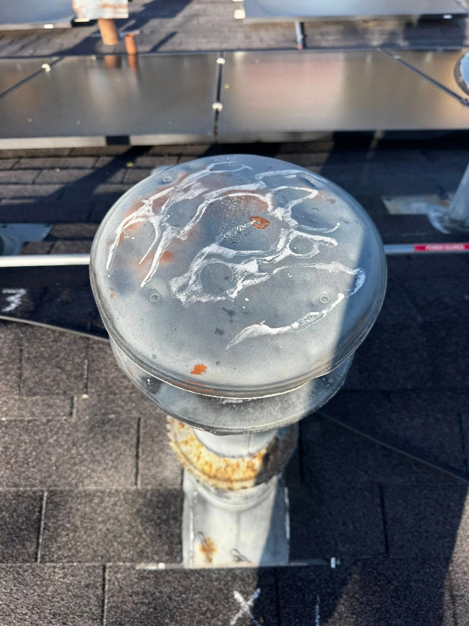 Close-up of a weathered metal dock bollard with cracked white paint on a rooftop deck.