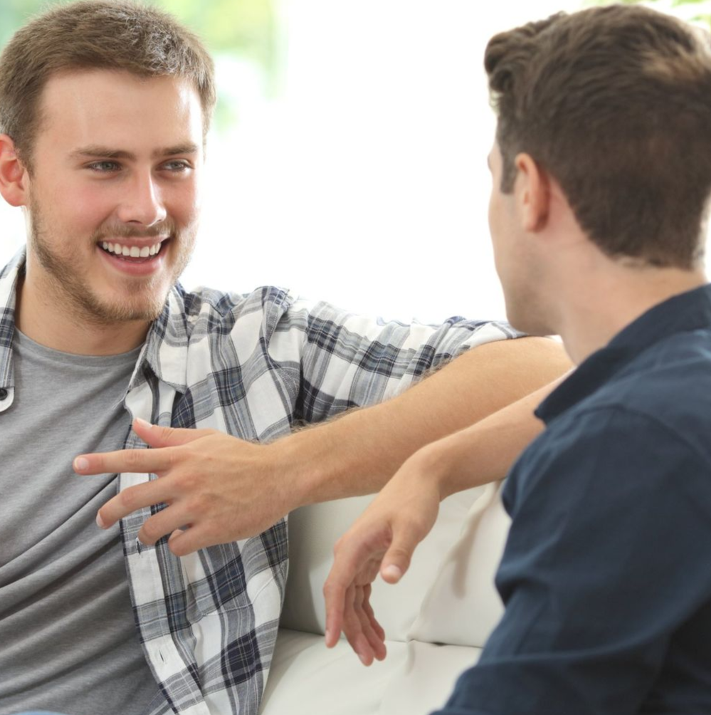 Two young men talking on a lounge, one offering support