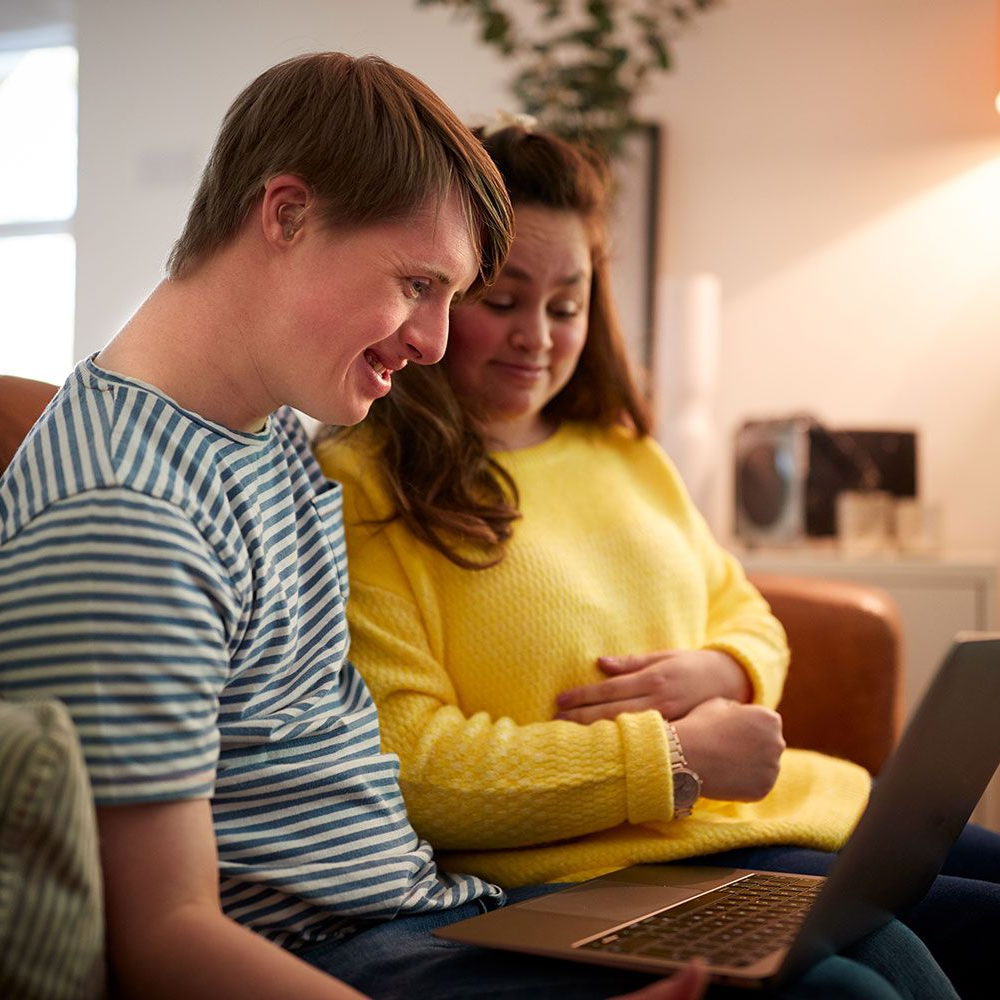 Two people with a disability using a laptop together at home