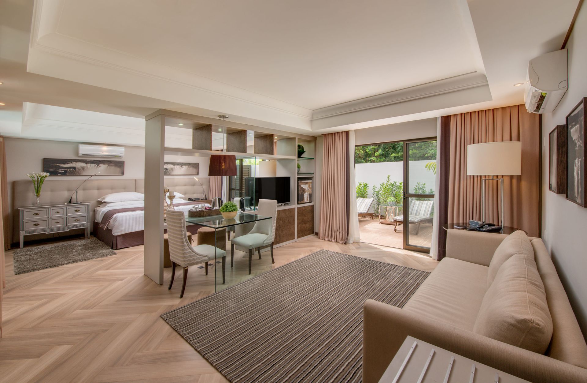 Suíte de hotel moderna com quarto, sala de jantar, sofá e varanda com vista.