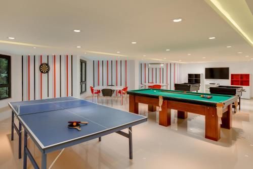 Sala de jogos com mesa de pingue-pongue, mesas de bilhar e decoração de parede listrada.