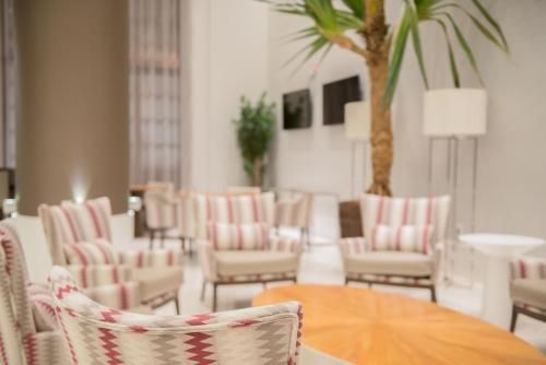 Sala de estar elegante com poltronas listradas, mesa de madeira e palmeiras altas em um ambiente iluminado.