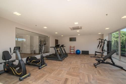 Sala de ginástica moderna com bicicletas ergométricas, esteiras, banco de musculação e grandes espelhos.