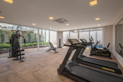Academia moderna com esteiras, aparelhos de musculação e grandes janelas com vista para a área verde.