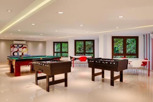 Sala de recreação com mesa de bilhar, mesas de pebolim e assentos sob iluminação embutida.