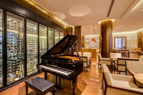 Sala de estar elegante com um piano de cauda, ​​adega climatizada e assentos aconchegantes em madeira e tons creme.