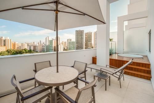 Pátio externo com mesa redonda, espreguiçadeiras e vista para o horizonte da cidade.