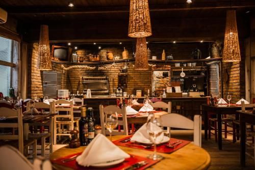 Sala de jantar rústica e aconchegante, com iluminação suave, mesas de madeira, luminárias de vime e lugares marcados.