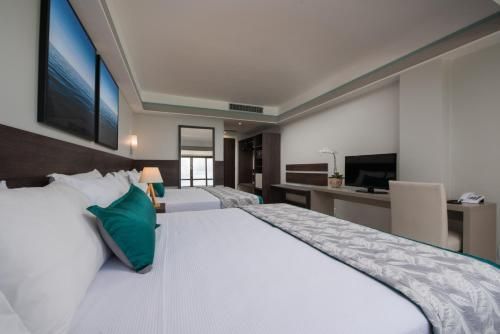 Quarto de hotel moderno com duas camas, obras de arte na parede e TV, visto da área da cama.
