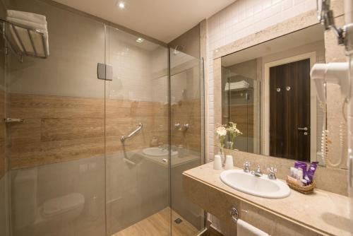 Banheiro moderno com box de vidro, azulejos bege e espelho de pia.