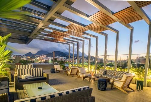Terraço na cobertura com lounge moderno, pérgola e vista para a cidade e as montanhas ao pôr do sol.