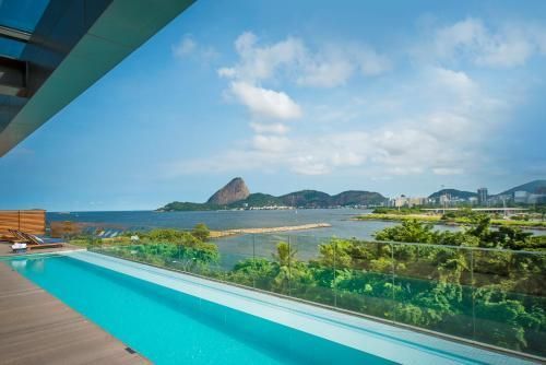 Piscina infinita com vista para a costa tropical e ilha rochosa sob um céu azul.
