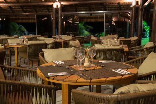Restaurante ao ar livre com mesas de madeira e cadeiras de vime sob iluminação aconchegante à noite.