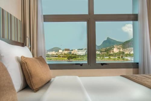 Cama de hotel junto à janela com vista para a montanha e para a cidade.