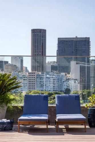 Duas espreguiçadeiras azuis em um terraço na cobertura com vista para o horizonte da cidade.