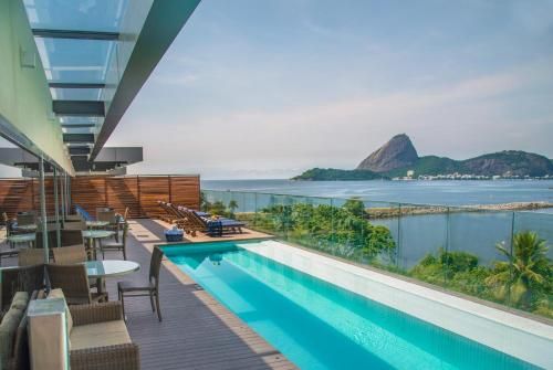 Terraço luxuoso com piscina, vista para o oceano e para a montanha ao longe, sob um céu límpido.