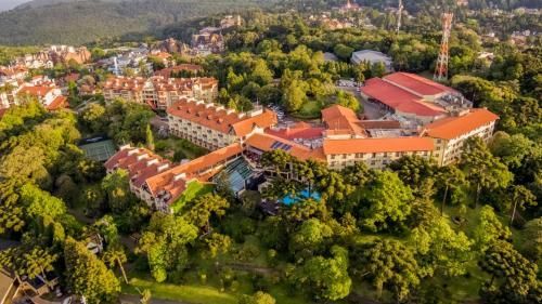 Vista aérea de um grande campus com telhado vermelho, cercado por densas árvores verdes.