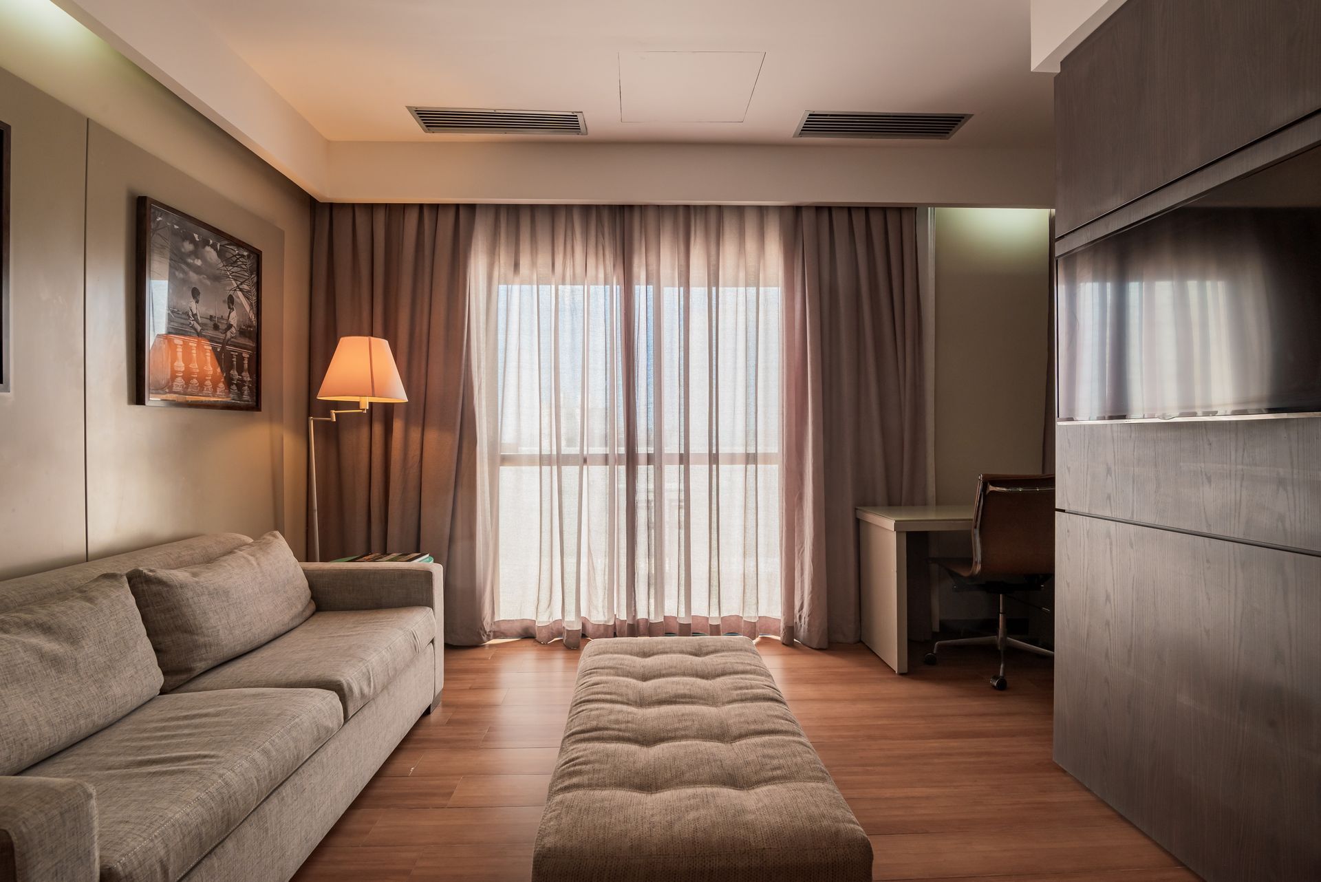 Sala de estar moderna com sofá branco comprido, painéis de madeira na parede, mesa de centro, suporte para TV e obras de arte emolduradas.