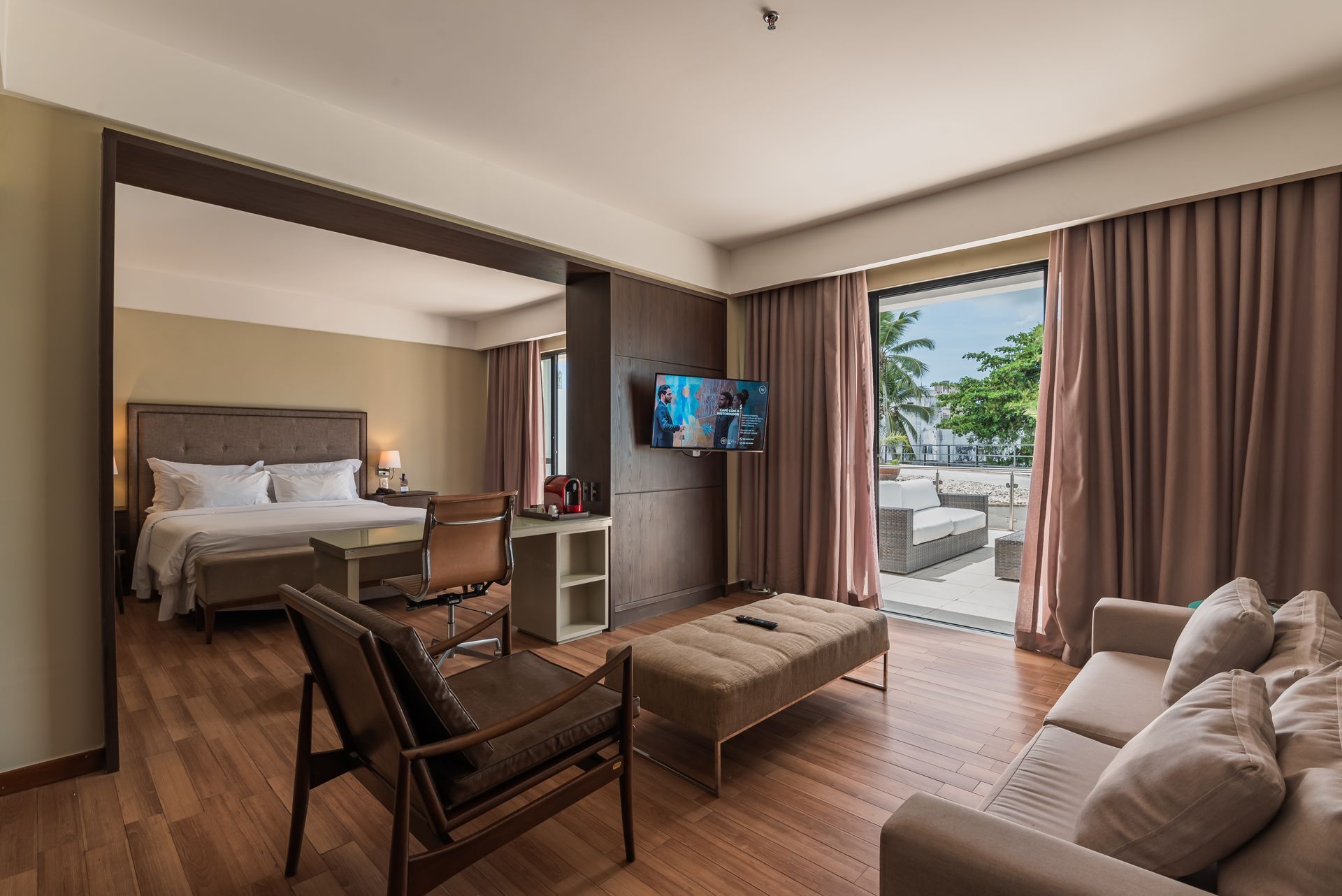 Sala de estar moderna com sofá bege, luminária, mesinha de centro, cadeira de madeira e parede com painéis de madeira sobre piso de madeira.