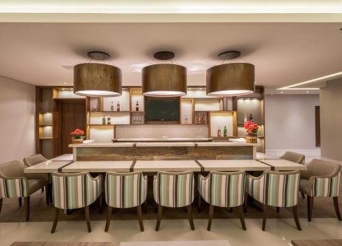Balcão de cozinha moderno com banquetas listradas, luminárias pendentes e uma bancada aconchegante de madeira e mármore.