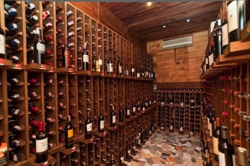 Adega de vinhos com prateleiras para garrafas embutidas nas paredes e no teto de madeira, e piso de azulejos.