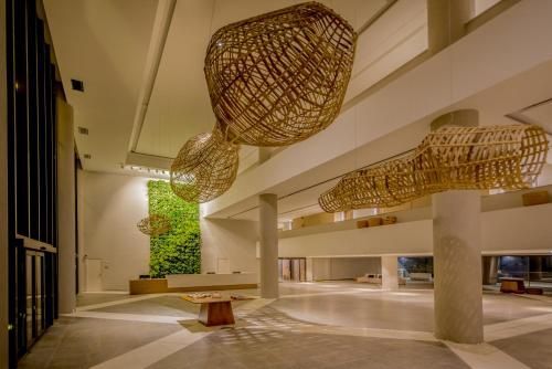 Hall de entrada moderno com luminárias pendentes de tecido trançado, colunas brancas e um jardim vertical verde.